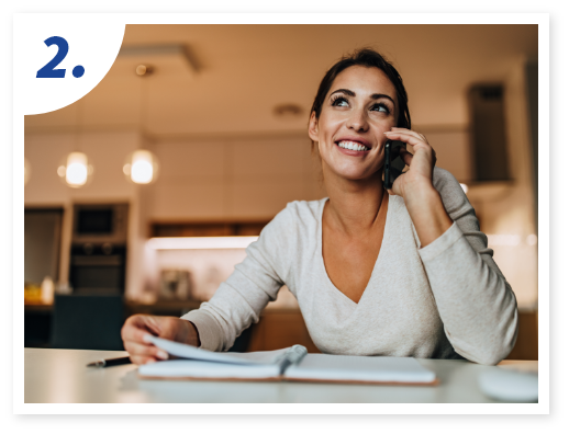 A woman in a cozy kitchen smiles while talking on the phone.