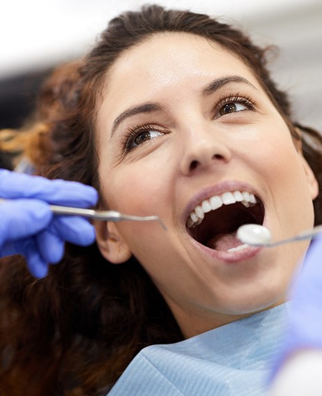Woman with brown hair in dental chair with mouth open about to undergo exam