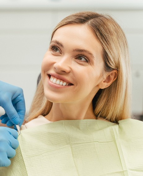 Dentist removing patient’s yellow drop cloth after treatments