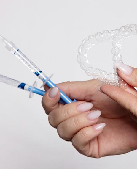 Woman&rsquo;s hands holding teeth whitening products