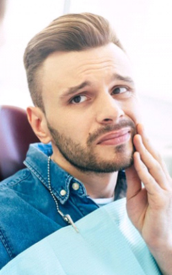 a patient holding his cheek due to tooth pain