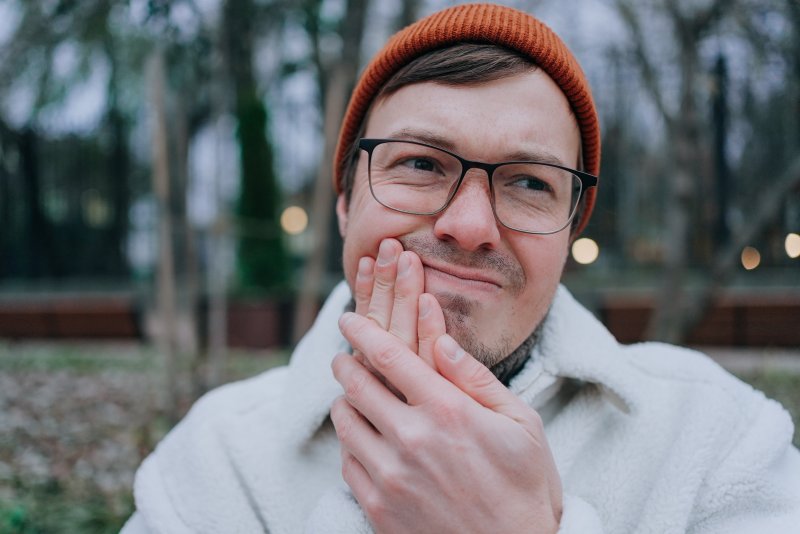 Young man holding his jaw because of toothache.