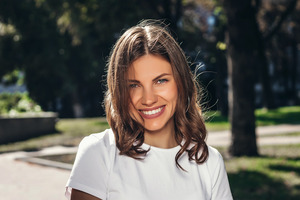 Woman in white shirt standing outside and smiling