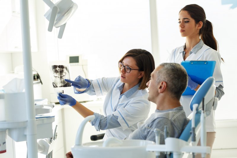 Dentist holding up X-ray of patient wanting dental implants